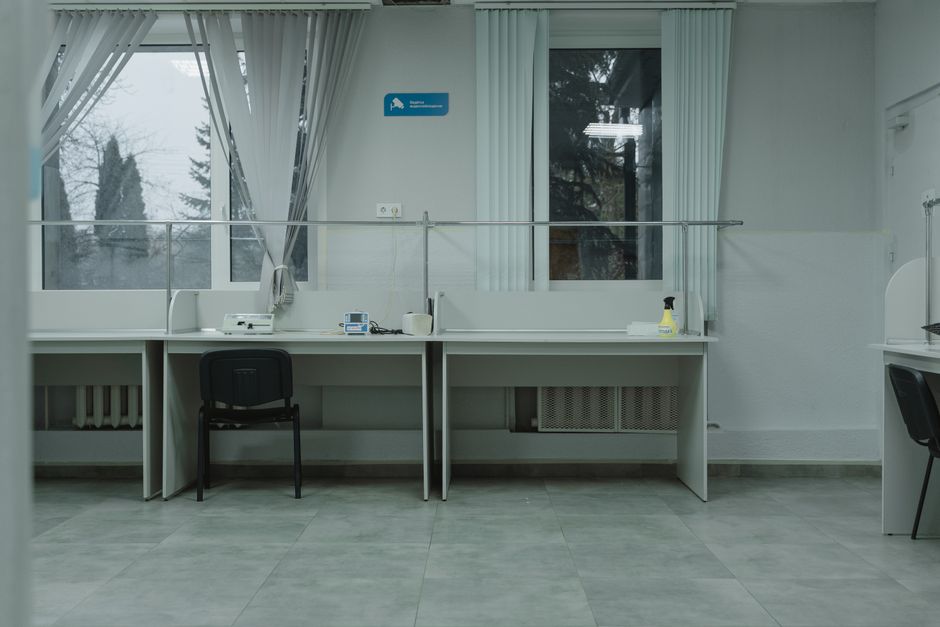 A clean and organized office space with desks, chairs, and large windows providing natural light.
