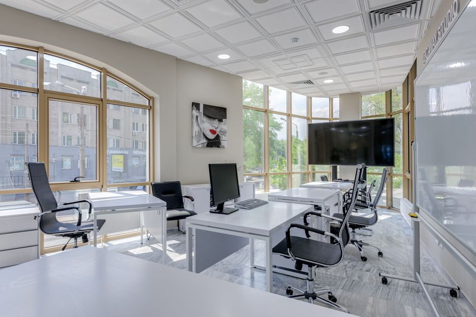 Contemporary minimalist office with glass windows and ergonomic chairs.